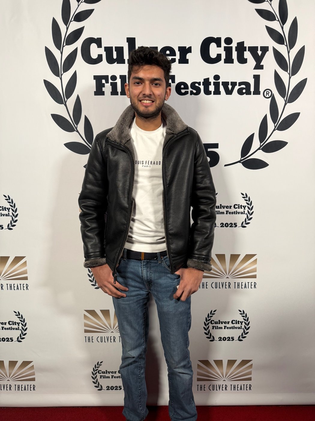 Devansh Saraf at the Culver City Film Festival, in a black shearling jacket in front of the festival backdrop